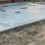 Fresh concrete slab laid out for building foundation with pooled water from rain