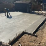 Construction workers preparing concrete slab surface