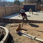 Construction workers using tools on freshly cured concrete slab